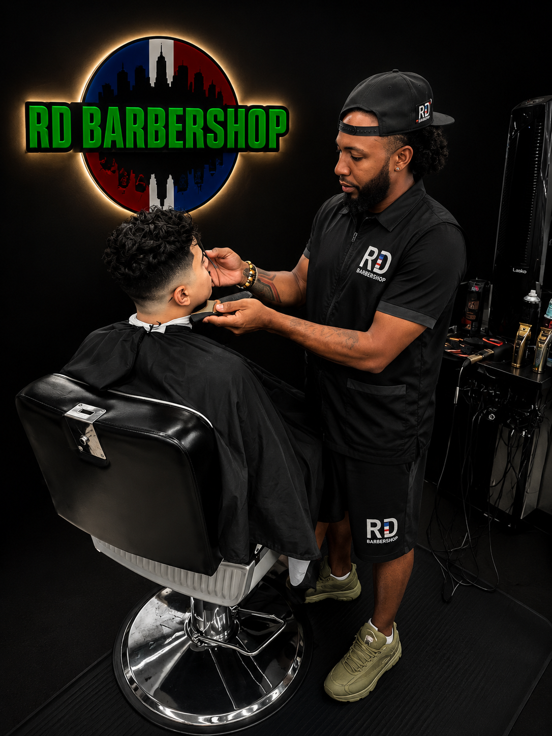 Barbero de RD Barbershop cortando el cabello de un cliente en la silla.